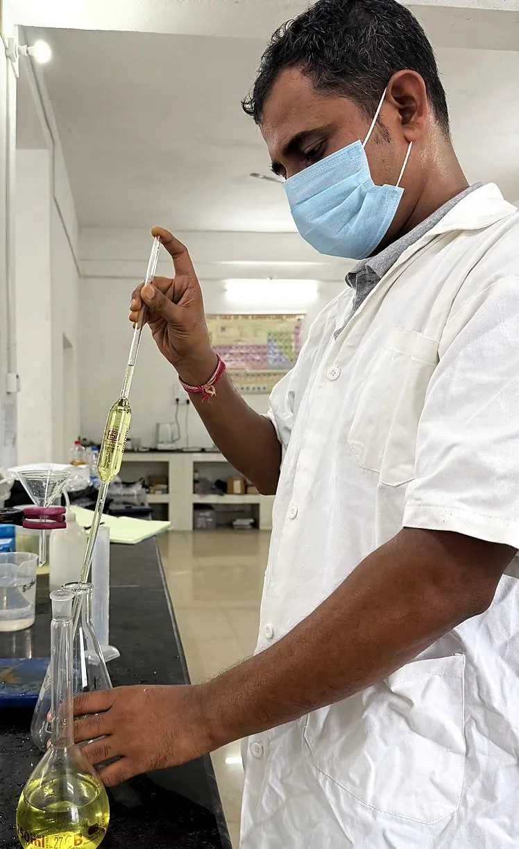 Analyst drawing a sample by pipette during wet chemical analysis